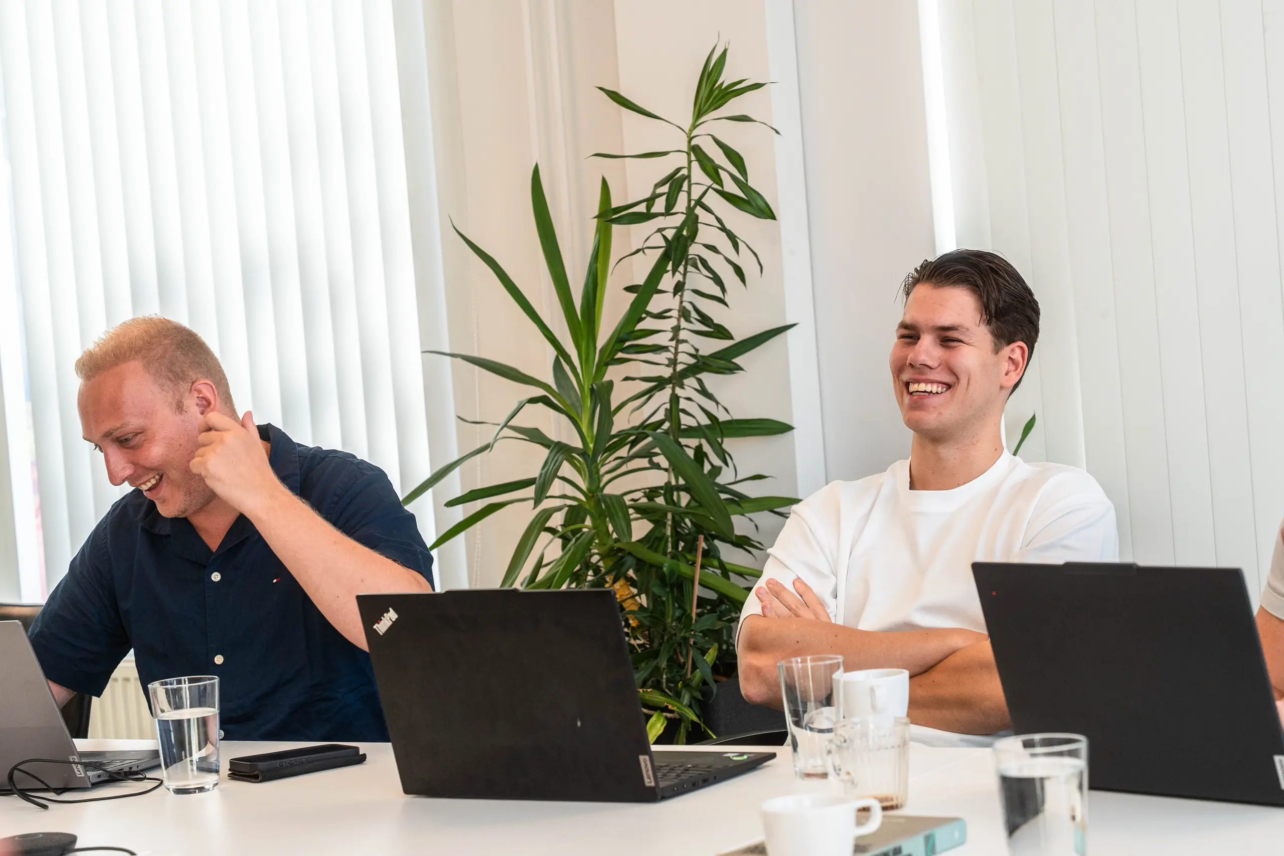 Twee adviseurs van adviesbureau De Vaart lachen samen tijdens het teamoverleg