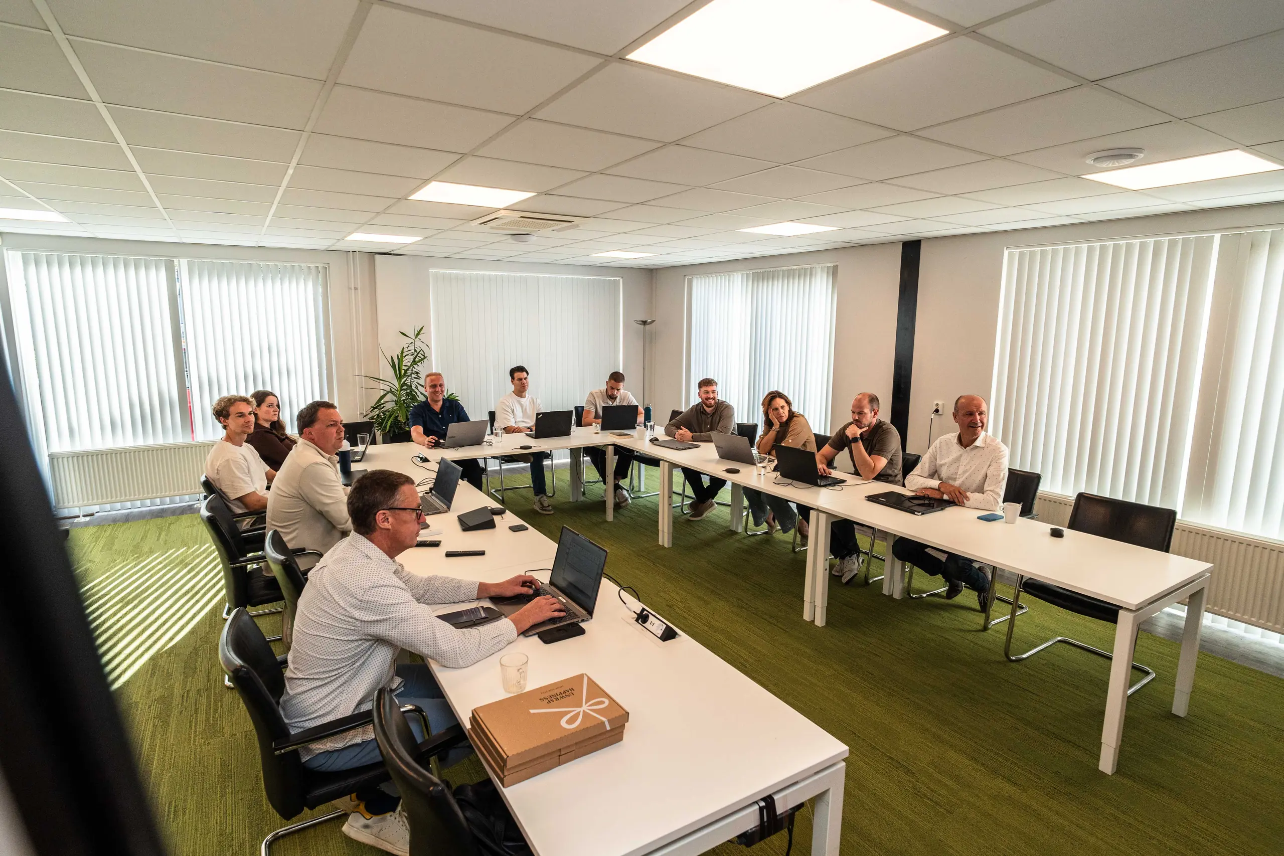 Het team van De Vaart zit samen aan tafel tijdens een presentatie