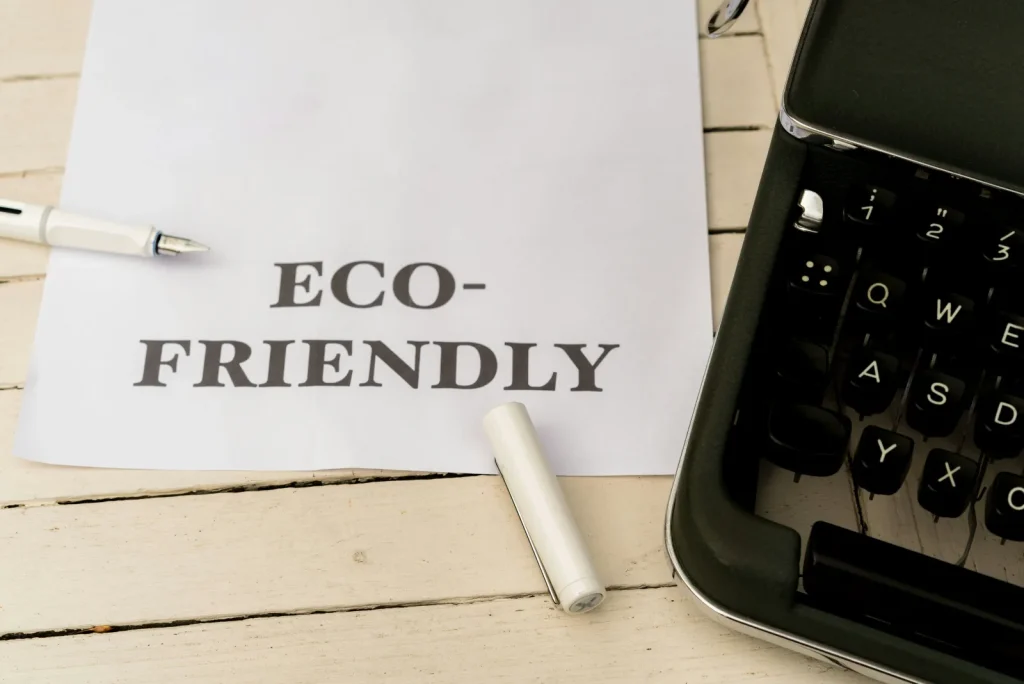 Vel papier met de tekst ECO-FRIENDLY naast een typemachine en pen, symbool voor duurzaamheidsbeleid dat je vastlegt