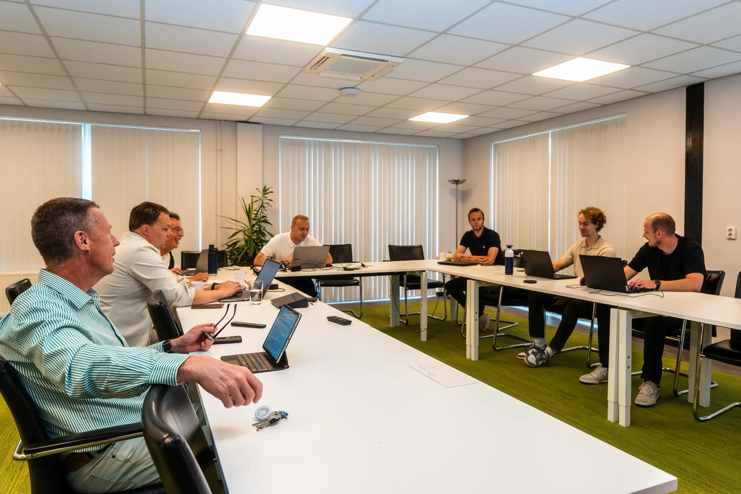 Overzicht van de vergaderzaal van organisatieadviesbureau De Vaart, met adviseurs aan het werk tijdens het overleg