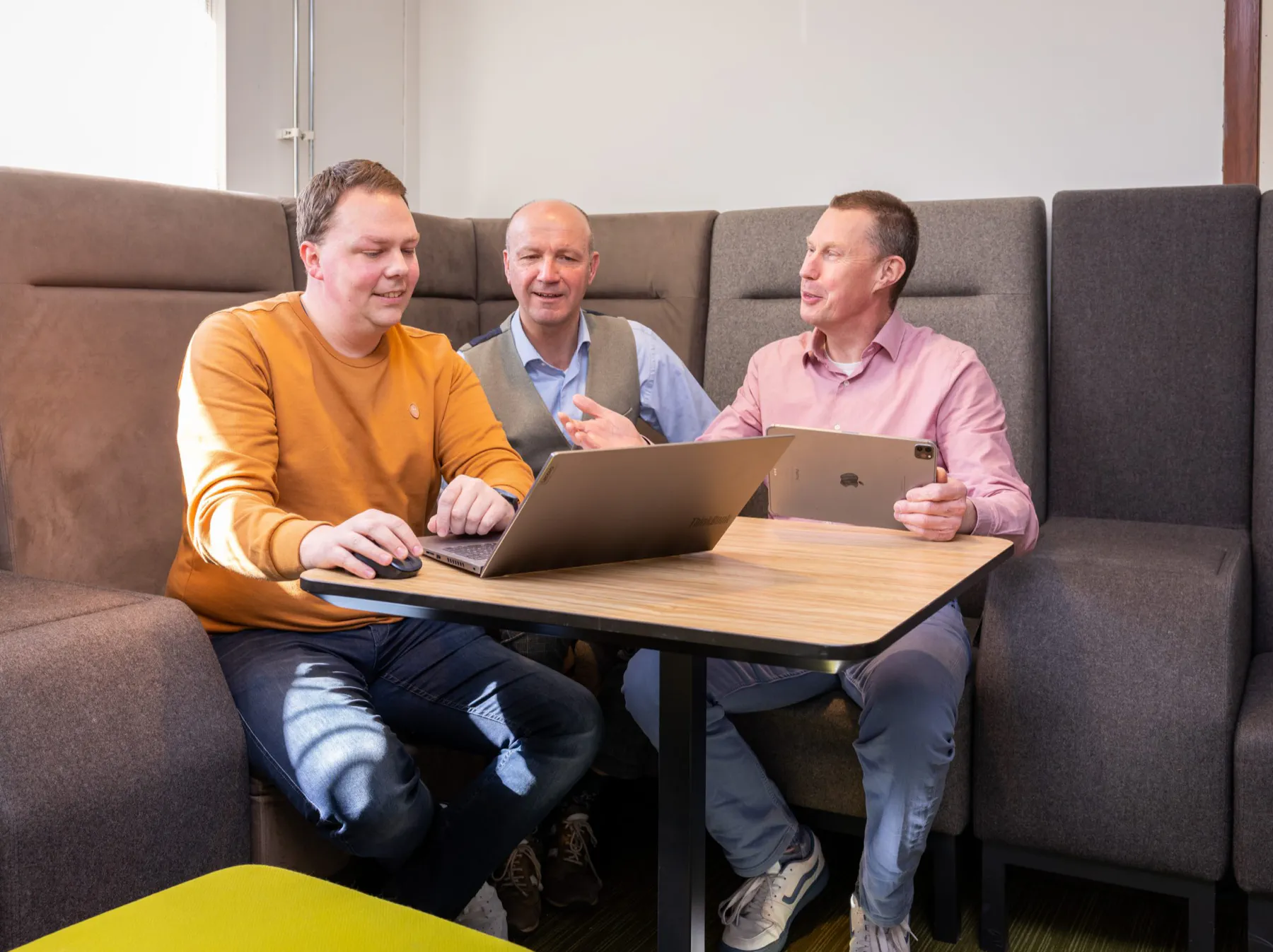 adviseurs-organisatieadviesbureau-de-vaart-overleg-laptop Drie adviseurs van organisatieadviesbureau De Vaart in overleg aan een tafel met laptop en tablet