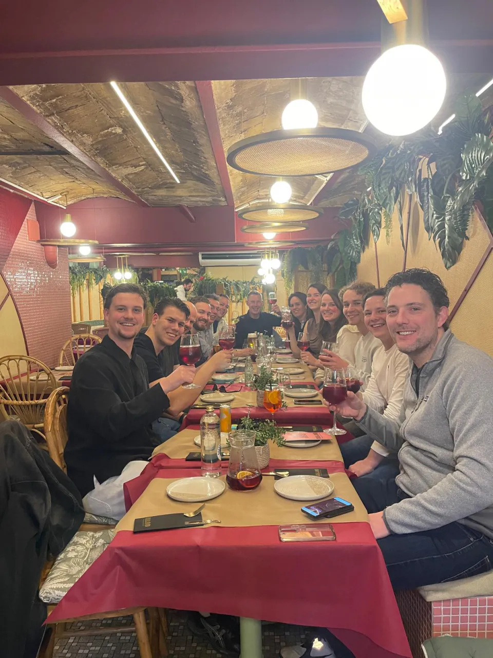 Collega’s van De Vaart proosten aan een lange tafel tijdens een teamdiner.